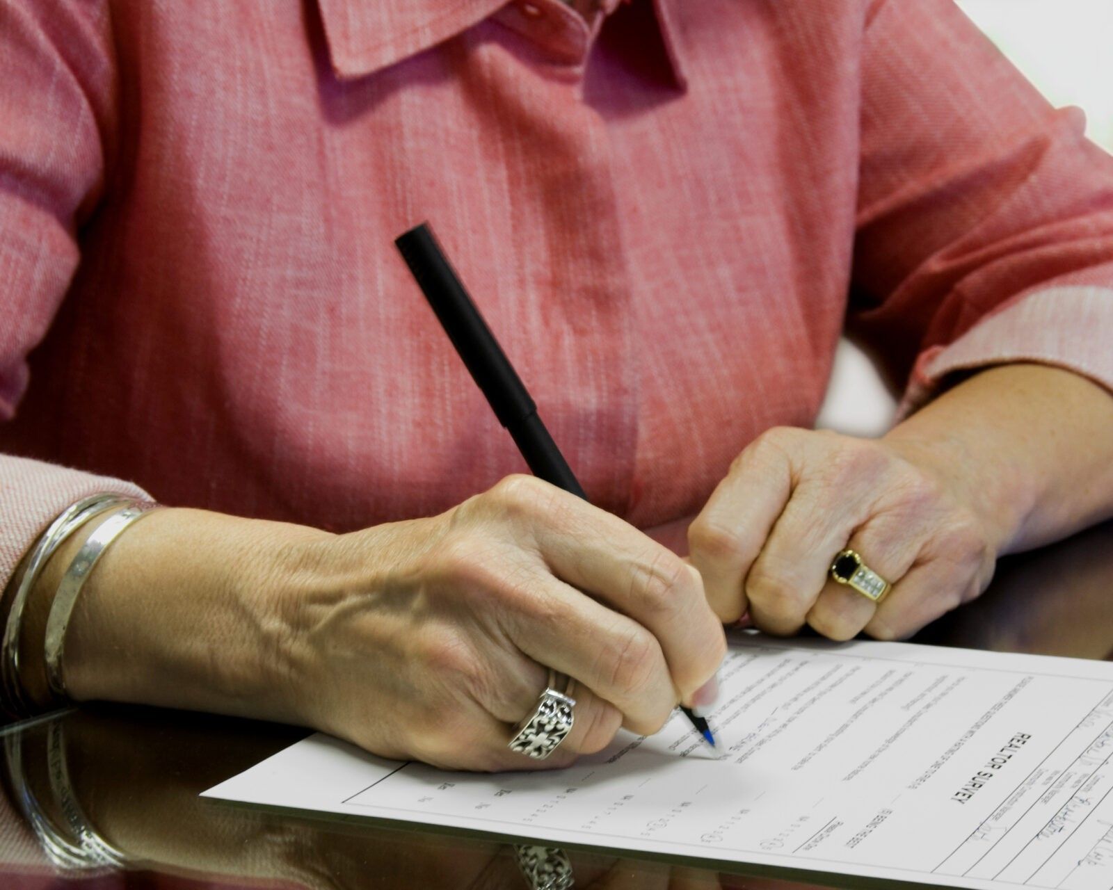 Person signing a document with a black pen to ensure Privacy Protection.