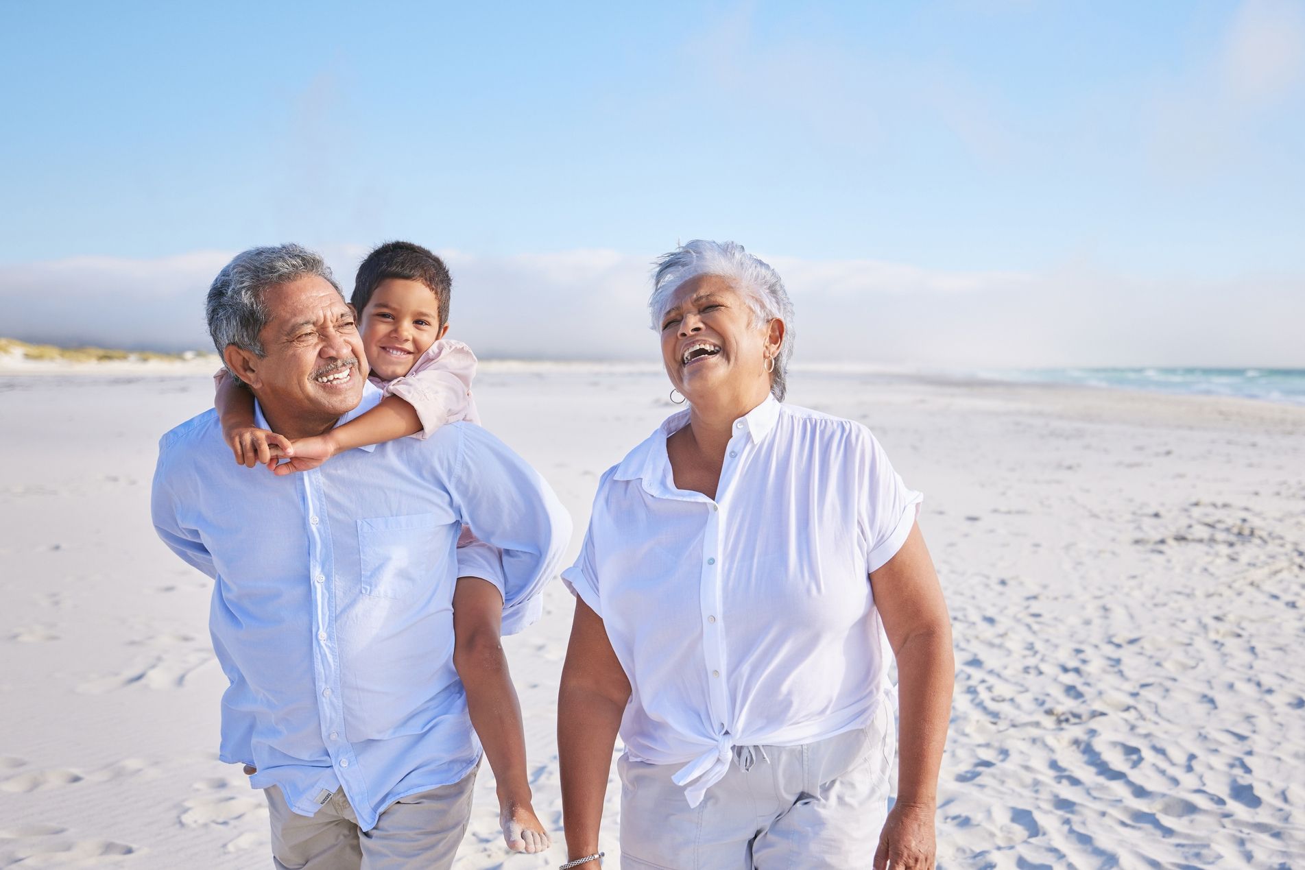 grandparents walking on the beach with their grandson