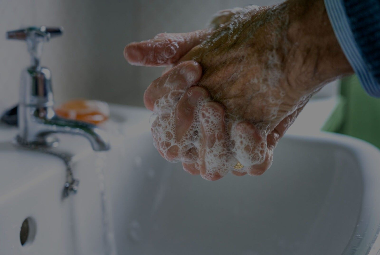 Person washing hands with soap and water at a sink, preventing respiratory infections.