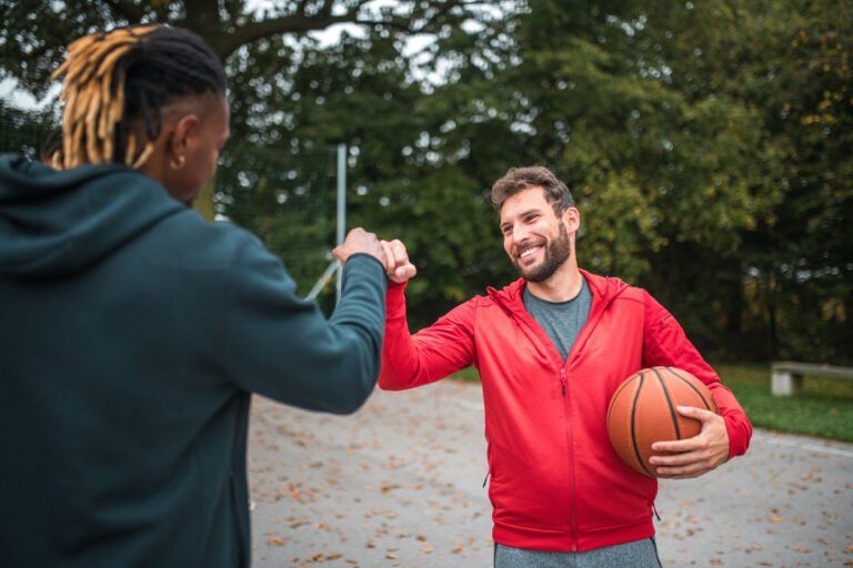 On the basketball court, a black male and Hispanic male celebrate with a triumphant fist pump after their game.