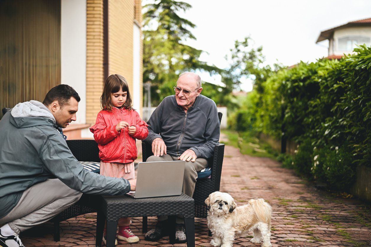 Multi generation family relaxing in a patio with laptop. Technology and education.