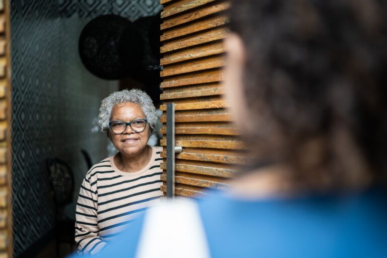 Senior woman open door to healthcare worker arriving at home