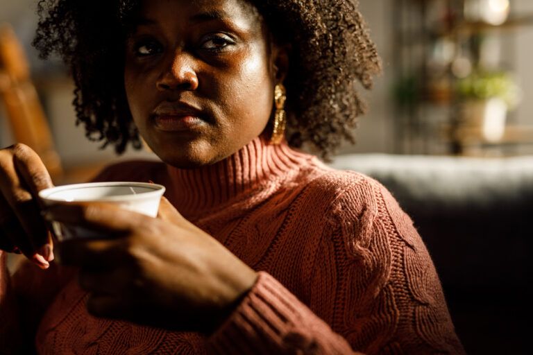 Worried young woman enjoying a cup of tea and contemplating