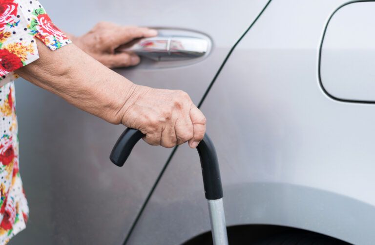 elderly woman open car door and holding walking stick