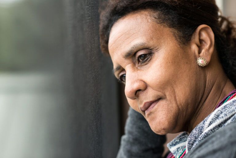 Thoughtful woman looking out a window with a pensive expression.