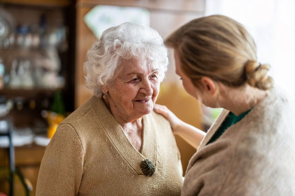 Caregiver gently comforting an elderly woman at home.