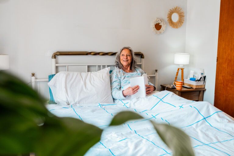Senior woman contemplating lying on bed at home