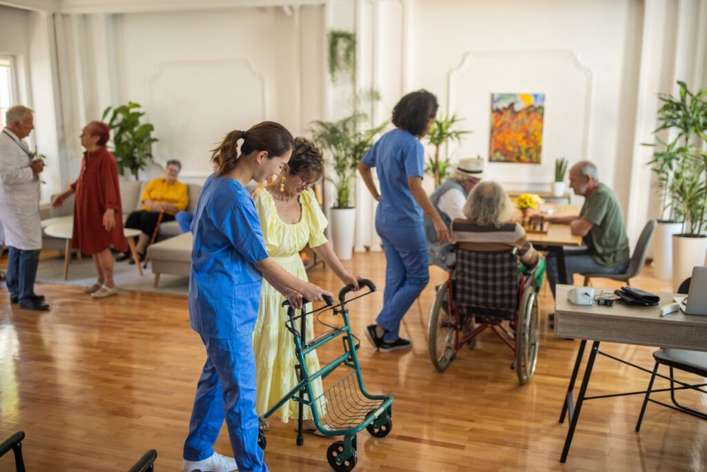 Healthcare workers assist and engage elderly residents in a bright, communal living space.