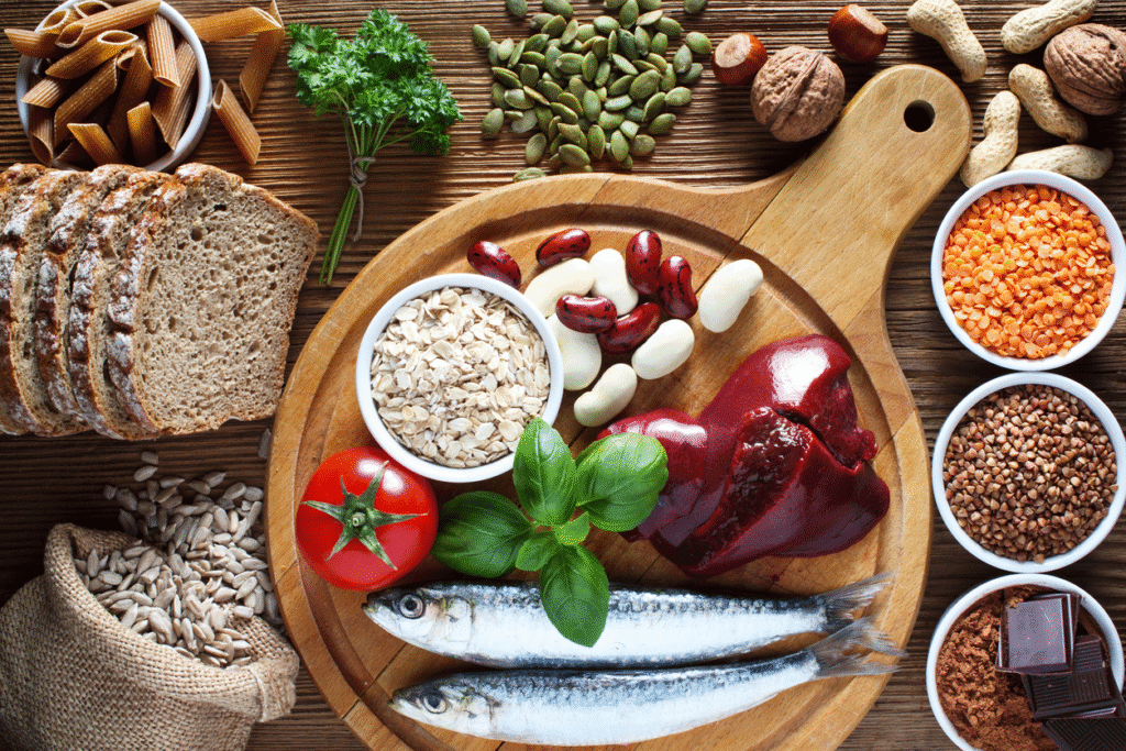 Foods such as liver, sardines, legumes, seeds, and whole grains on table