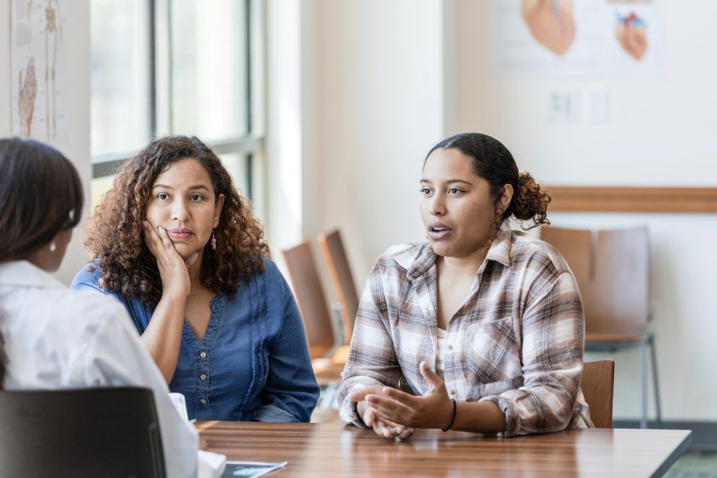 Two women having a serious conversation with a doctor in a medical office