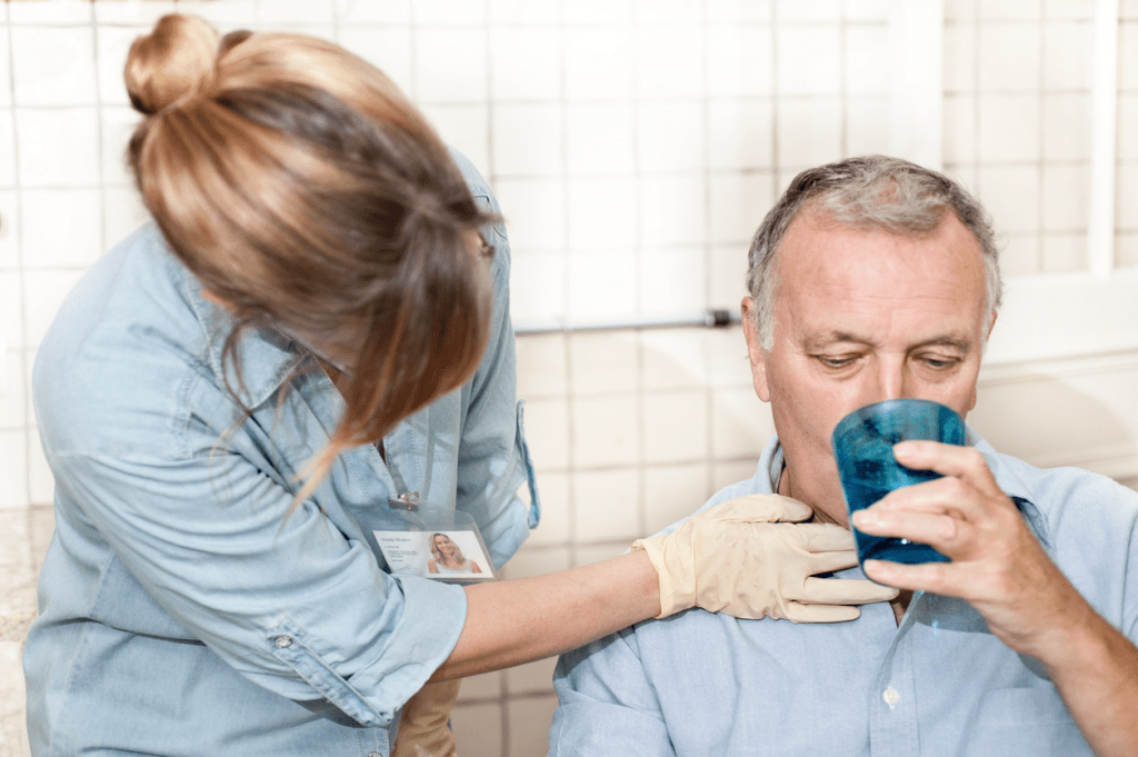 A speech pathologist conducts a swallowing test with a stroke patient.