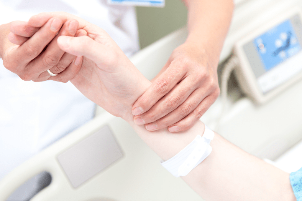 Healthcare worker checking patient's pulse on wrist in hospital bed