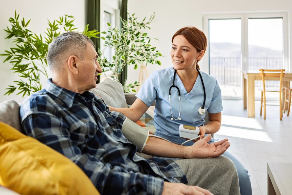 A nurse wearing blue scrubs and a stethoscope takes a stroke survivor’s blood pressure using a blood pressure cuff.