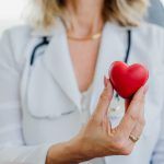 Doctor holding a red heart model to represent heart health and care.