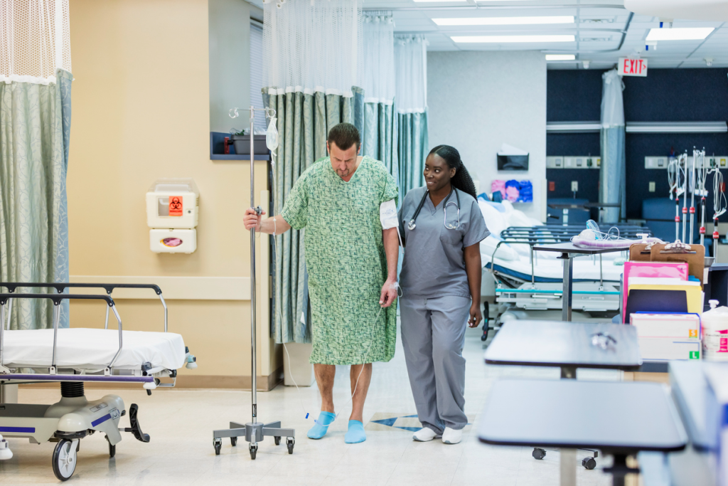 Nurse helping patient walk with IV pole in a hospital corridor