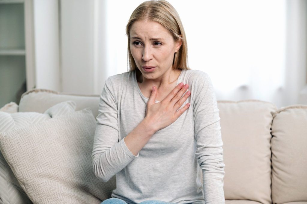 Woman clutching chest and appearing short of breath