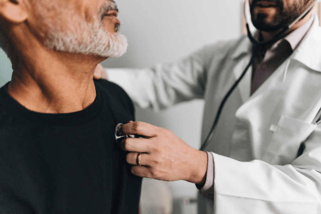 Doctor using a stethoscope to check a patient's chest during a medical exam.