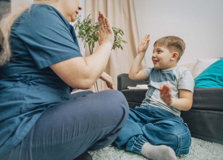 Therapist and child smiling while practicing hand clap game