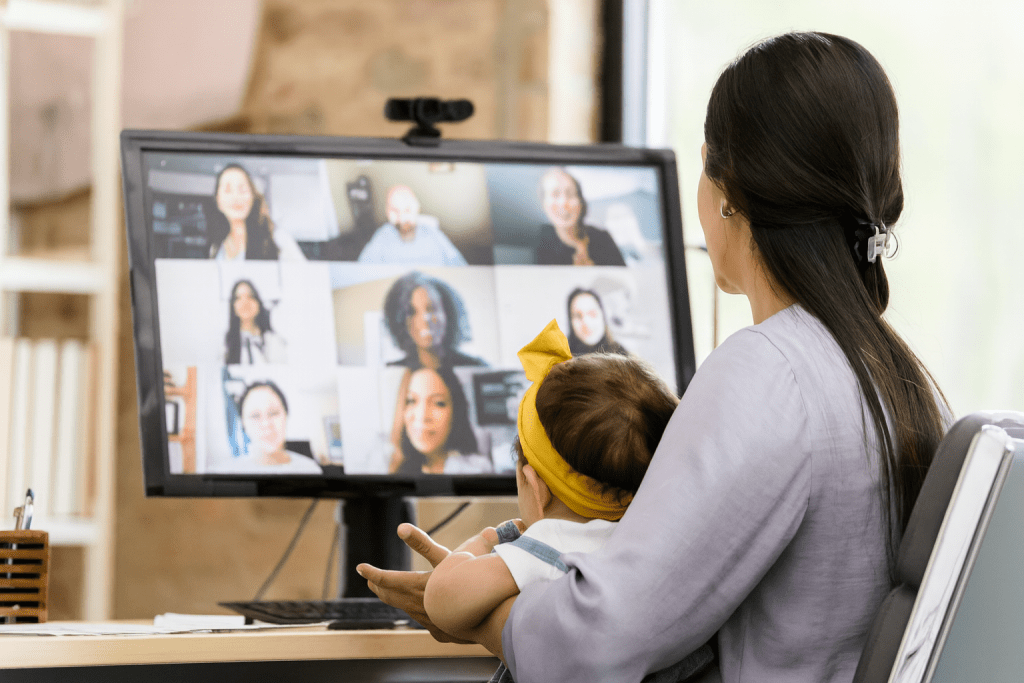 Mother with baby attending online video support group meeting on computer