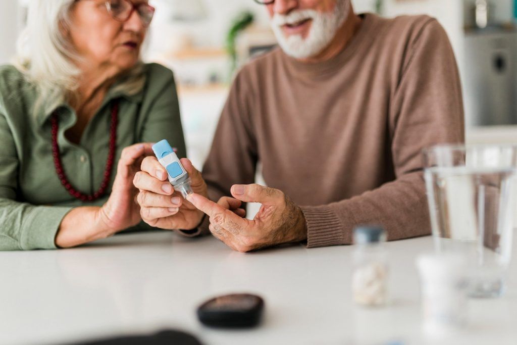 Older couple checks blood sugar with glucose meter.