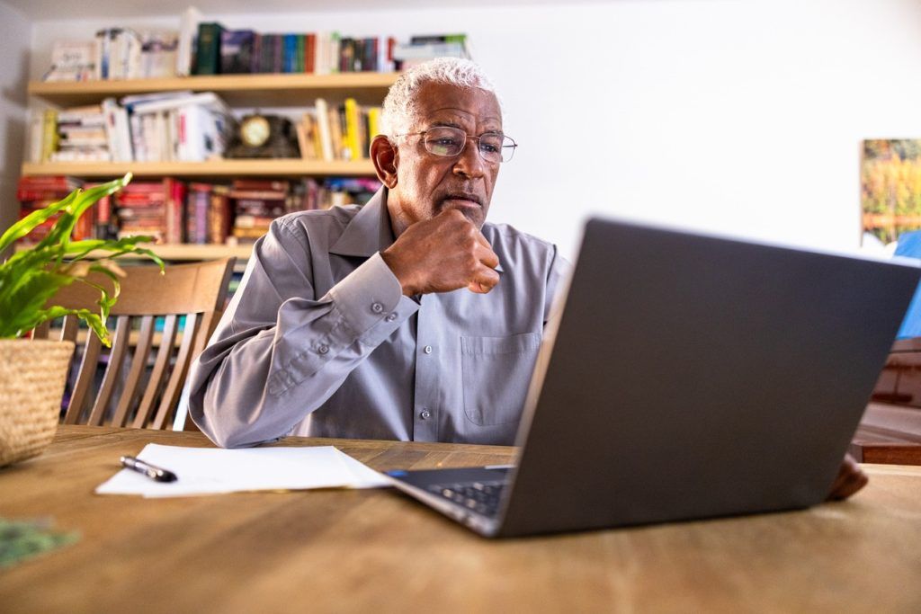 Older man researches diabetes care on laptop at home.