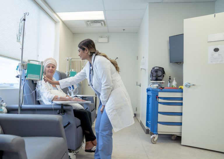 Doctor checking on a patient receiving chemotherapy in an infusion clinic.