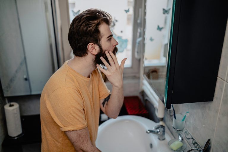 Man examining his mouth in a bathroom mirror.