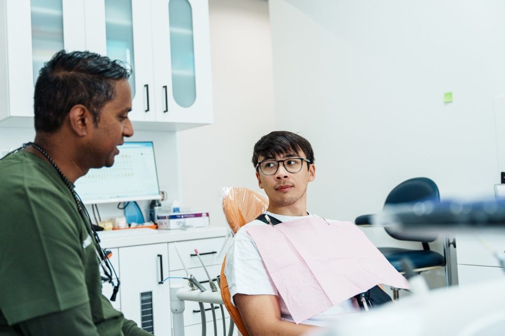 Dentist talking with a patient seated in a dental chair.