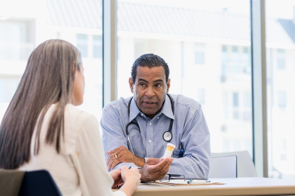 Doctor discussing a prescription bottle with a patient.