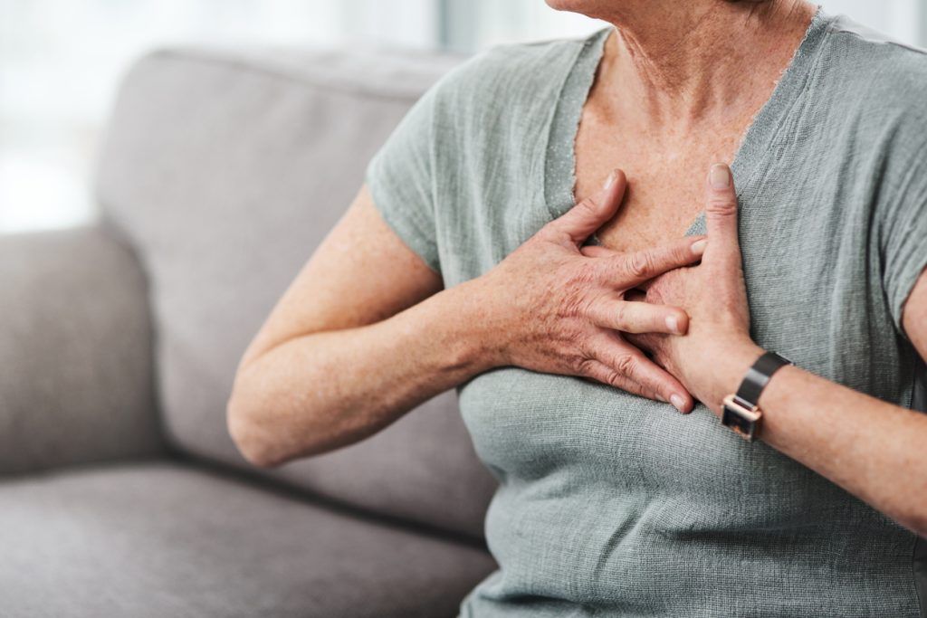 A woman clutching her chest due to difficulty breathing, which is a symptom of Interstitial Lung Disease.
